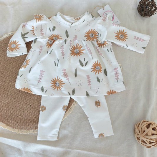 Conjunto de minivestido de bebé con estampado de girasoles naranjas en fondo blanco. Se cierra en el hombro con dos snap. Completado en la parte inferior por mallas del mismo estampado.