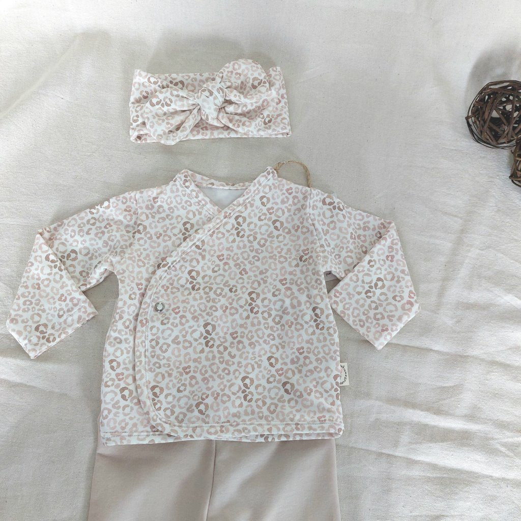 Vista de la camisa del conjunto de recién nacido con cierre en el lateral de la barriga de camisa de animal-print y diadema a juego.
