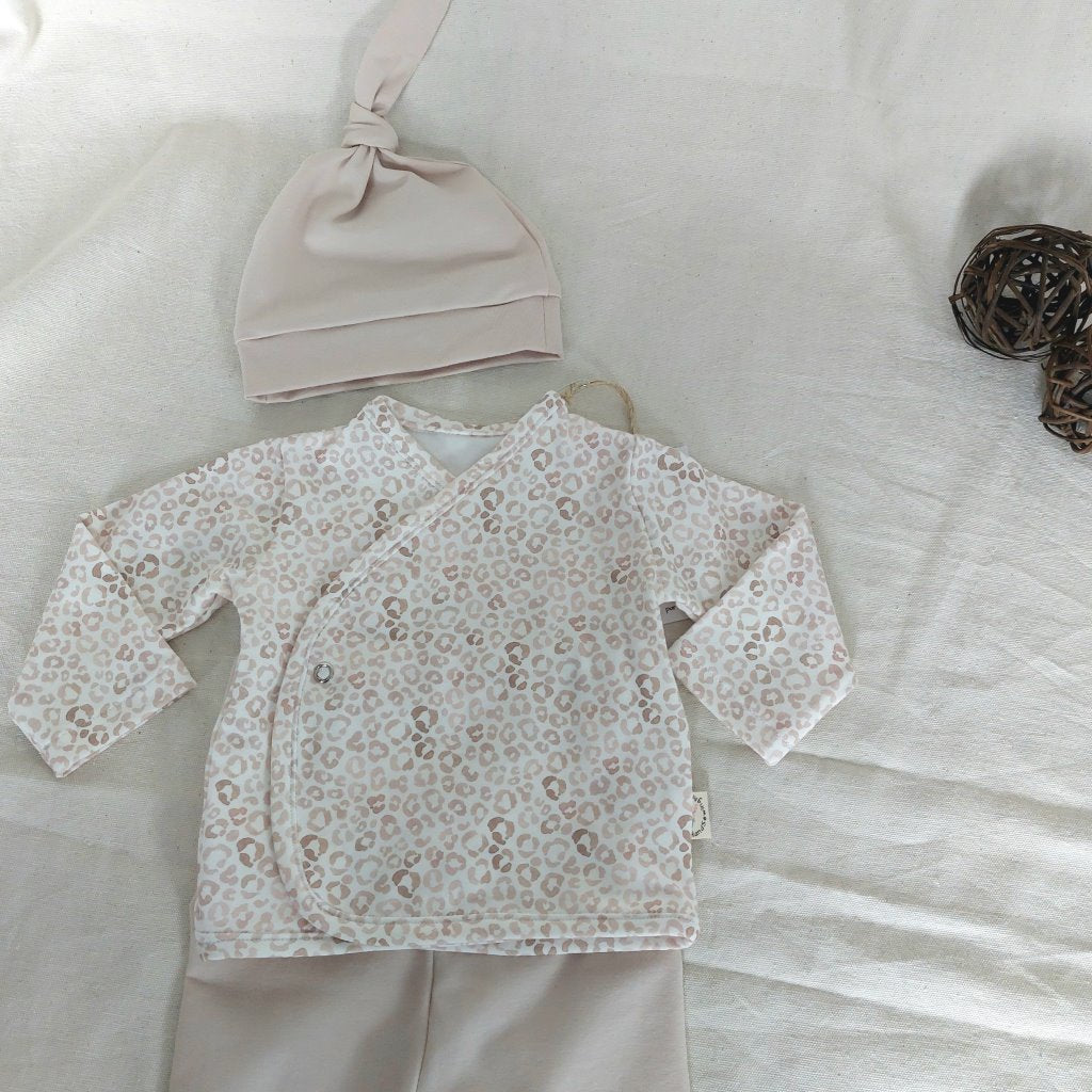 Vista de la camisa del conjunto de recién nacido con cierre en el lateral de la barriga de camisa de animal-print y gorro de un nudo de color beige.