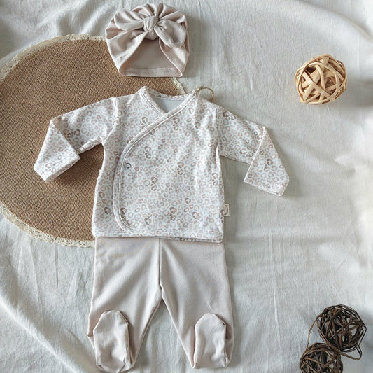 Conjunto de recién nacido, compuesto por camisa con cierre en el lateral de la barriga de estampado de animal-print. Completado con turbante y polainas de color beige.