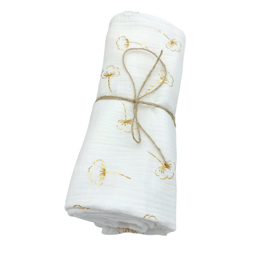 Mantita de Muselina, enrollada atada con un lazo de hilo de yute. El estampado es de flores de algodón doradas sobre mullido blanco
