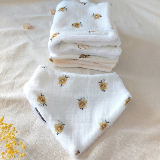 Dos toallas de lactancia dobladas y apiladas en la parte superior con estampado de florecillas marrón claro sobre mullido blanco, se completa con una bandana de bebé del mismo estampado en la parte inferior 