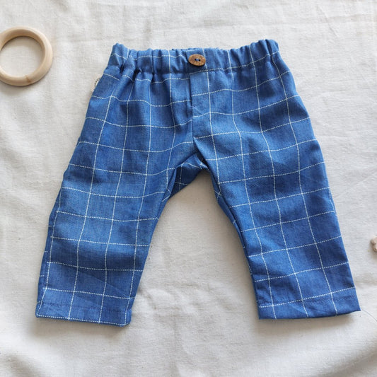 Vista frontal de pantalón de bebé largo tejano de cuadros azules con su botoncito en la cintura.